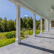 porch of two story white country style home with an expansive yard